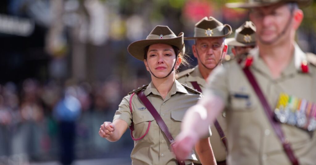 Female military personnel marching in a parade, leading a group of soldiers, focused and in uniform